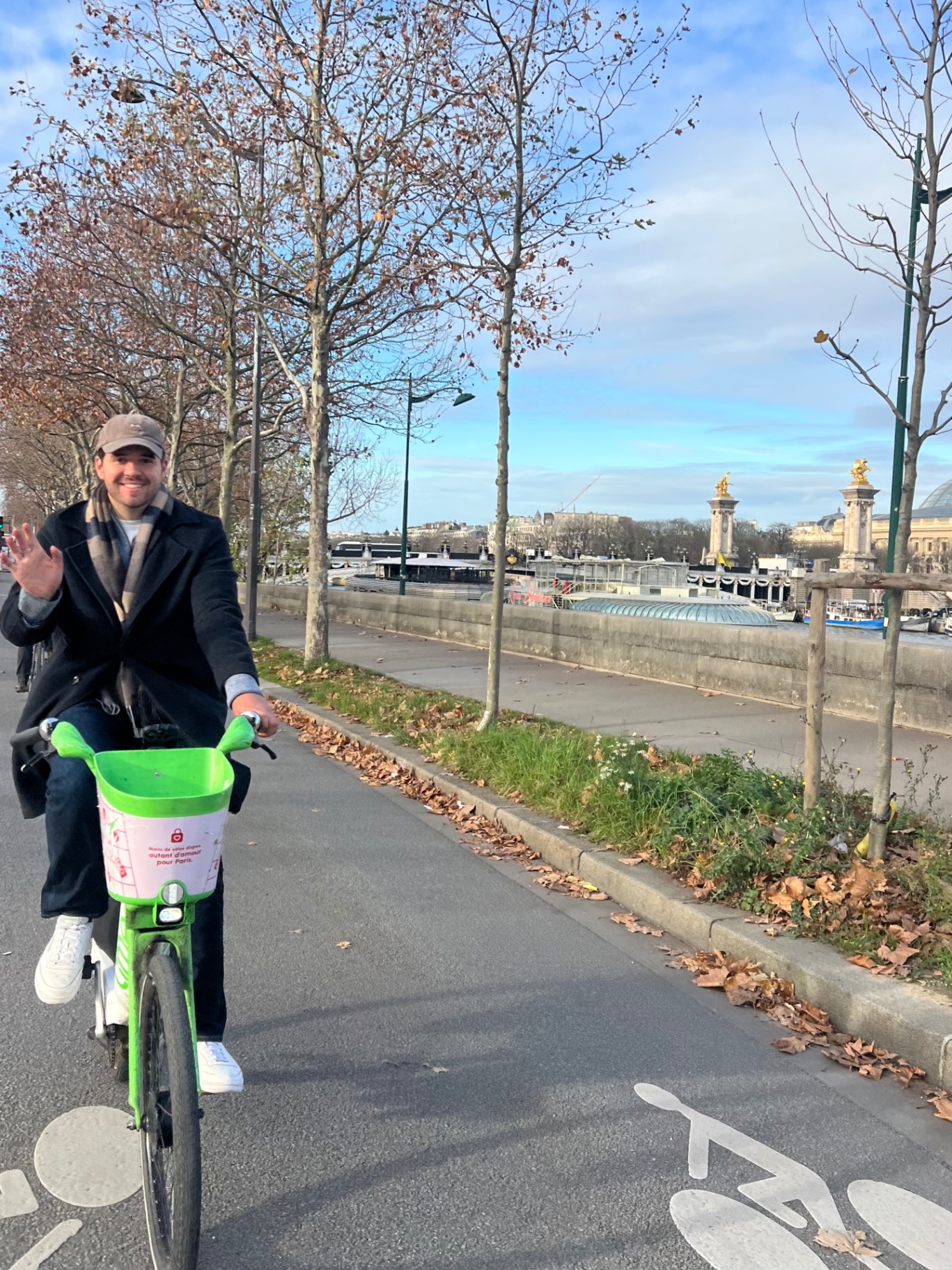 Riding a bright green Lime bike along the Seine in Paris with Pont Alexandre III visible in the background.