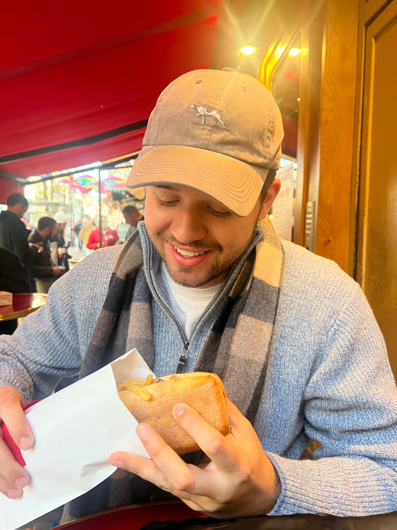 A Paris café lunch moment with a filled baguette and fries at a red-awning bistro, matching the takeaway lunch stop in the itinerary.
