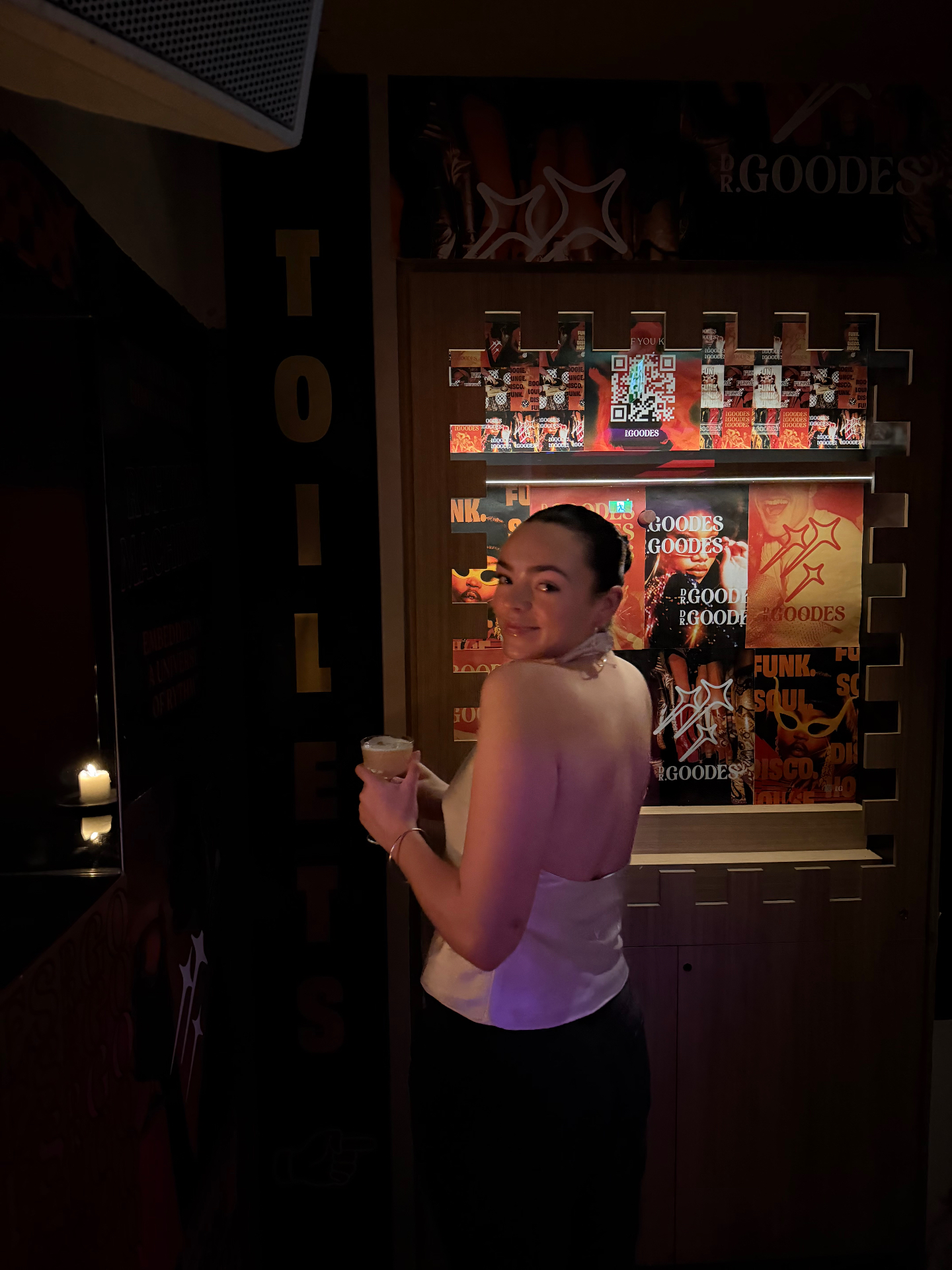 A guest holds a frothy 'Lola' cocktail at DrGoodes in Paddington, Sydney — a tropical medley of coconut rums and citrus at the disco-soaked boogie lounge whose moody poster wall of funk and soul artwork has made it one of the best new cocktail bars in Sydney.