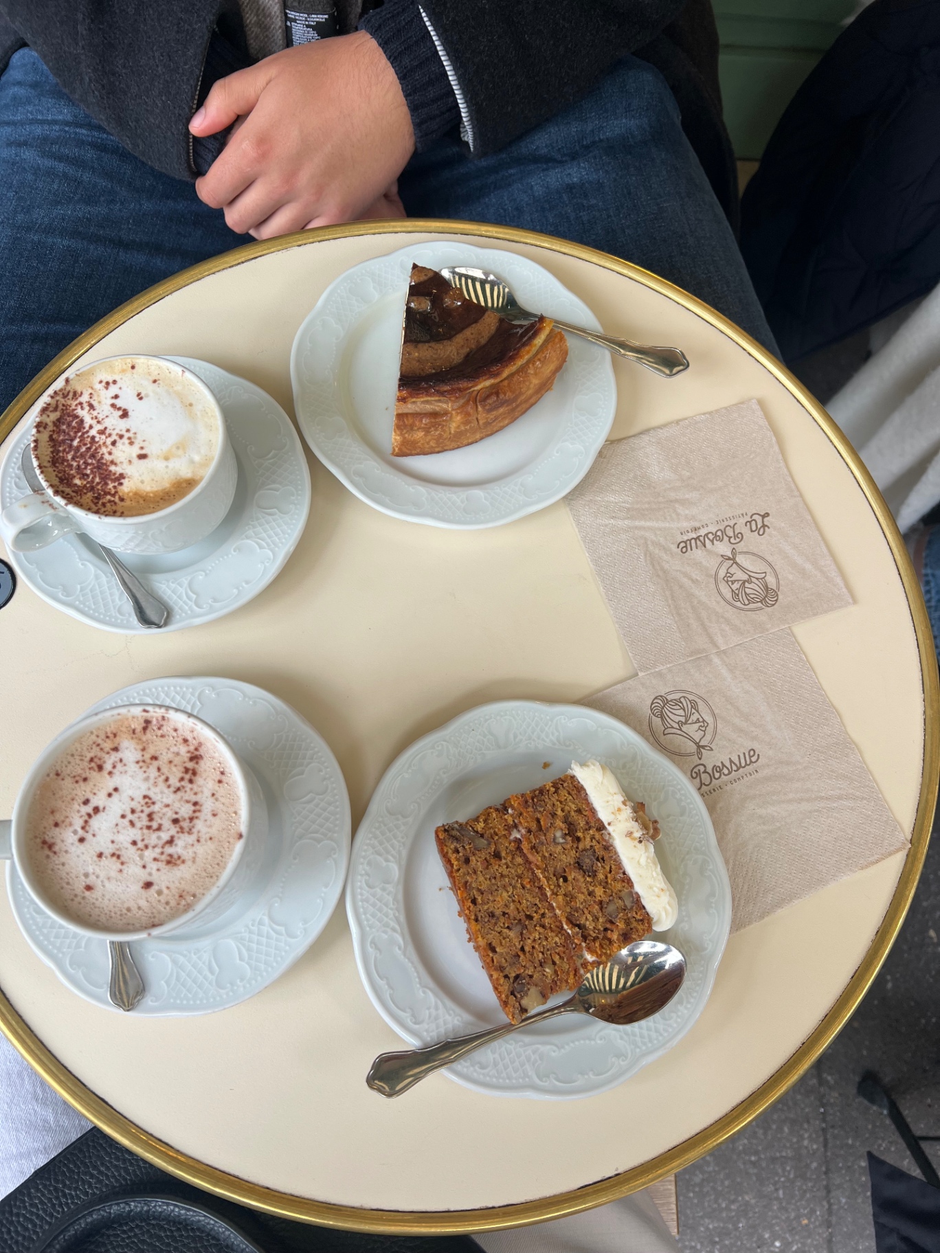 Two coffees and two slices of cake on marble-edged plates at La Bossue in Montmartre, with the café's napkins on the table.